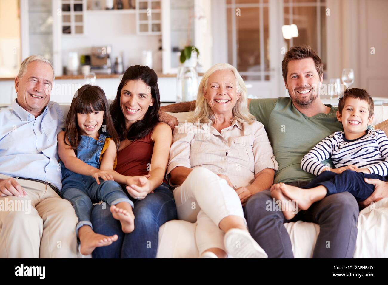 Gerne drei Generation weiß Familie auf einem Sofa zusammen zu Hause sitzt lächelnd auf Kamera, Vorderansicht Stockfoto