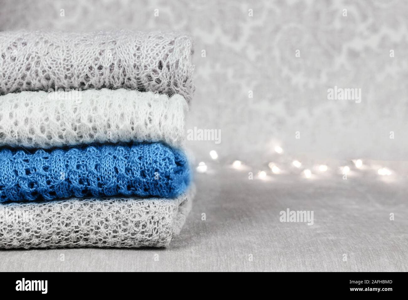 Stilvolle gestrickt, pastellfarbenen Pullover und eine trendige blaue Farbe in verschiedenen Strickmuster auf Samtigen Stoff Hintergrund stack gefaltet. Wint Stockfoto