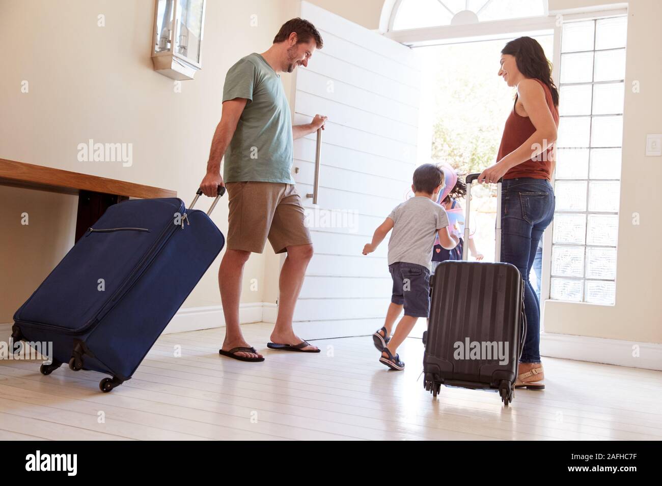 Mitte nach weißen Ehepaar und Kinder verlassen ihr Zuhause mit Gepäck in den Urlaub zu gehen, volle Länge Stockfoto