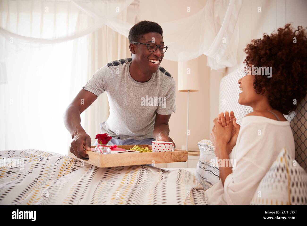 Tausendjährigen afrikanischen amerikanischen Paar feiern, Mann seinen Partner, Frühstück im Bett, in der Nähe Stockfoto