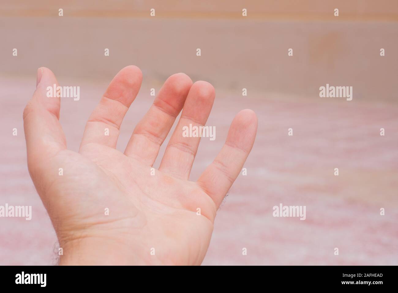 Konzeptionelle offene Hand ausstrecken auf weichem orange hinterlegt. Offenheit, Hingabe, Hilfe und Unterstützung. Stockfoto