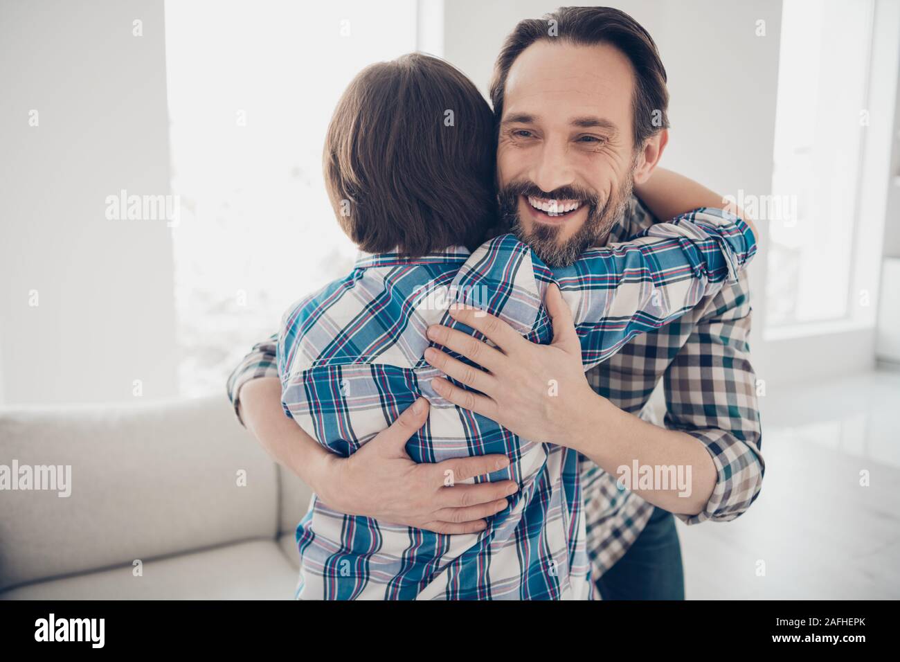 Close-up Portrait von zwei netten attraktiven schöne fröhliche fröhliche Jungs dad und vor - jugendlich Sohn treffen Tag umarmen in Licht, weißes, modernes Interieur. Stockfoto