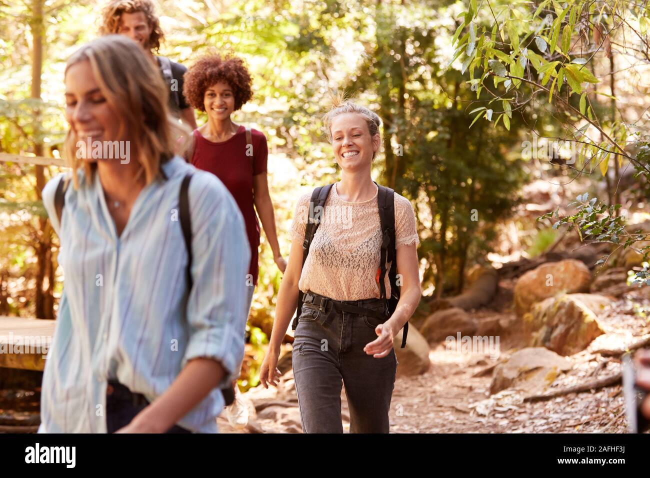 Lächelnd tausendjährigen Freundinnen zusammen zu Fuß bei einer Wanderung im Wald, in der Nähe Stockfoto