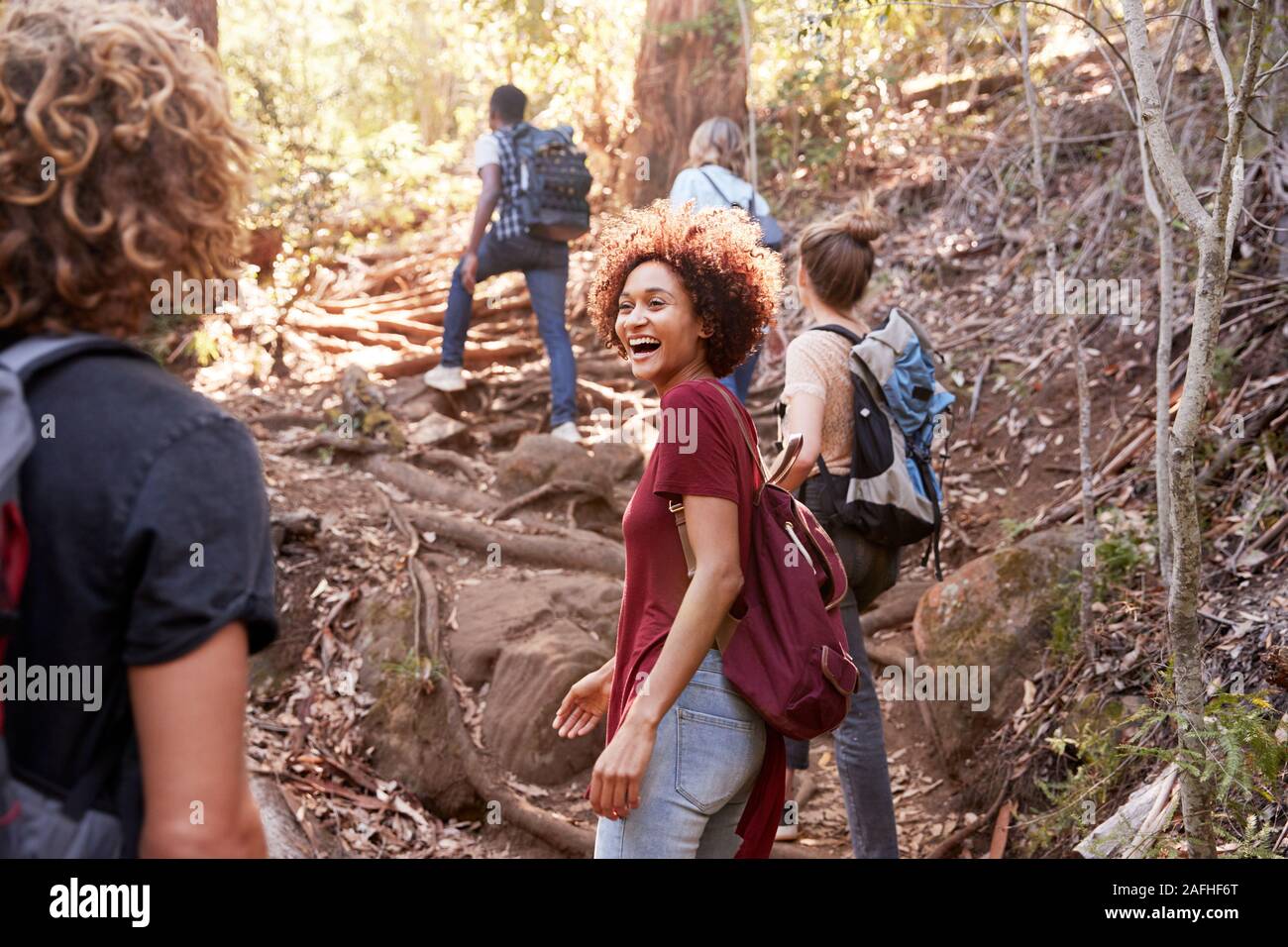 Gruppe der tausendjährigen Freunde bergauf wandern auf einem Forstweg, drei Viertel Länge Stockfoto