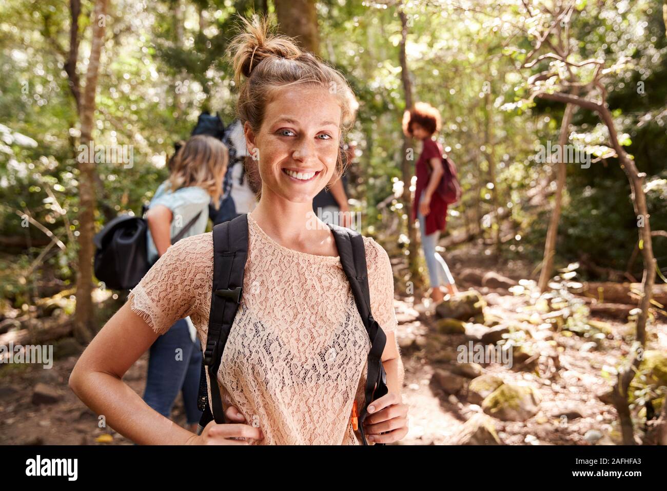 Portrait der tausendjährigen weiße Frau mit gebunden Haar wandern in einem Wald mit ihren Freunden, in der Nähe Stockfoto