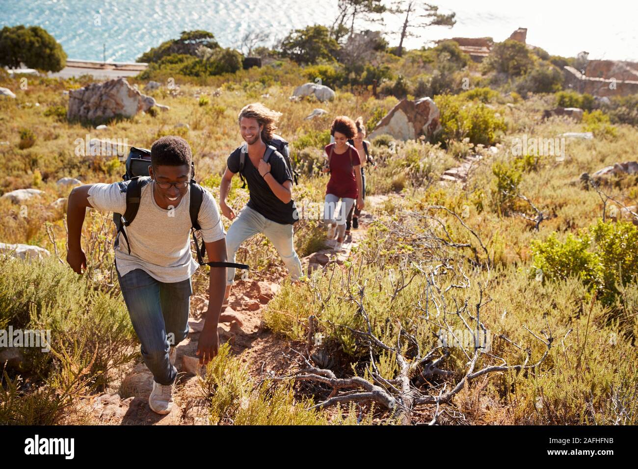 Drei junge erwachsene Freunde Wandern auf einem Weg von der Küste, volle Länge Stockfoto