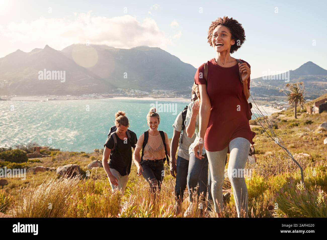 Tausendjährige afrikanische amerikanische Frau, die Freunde auf eine ansteigende Wanderung an der Küste, in der Nähe Stockfoto