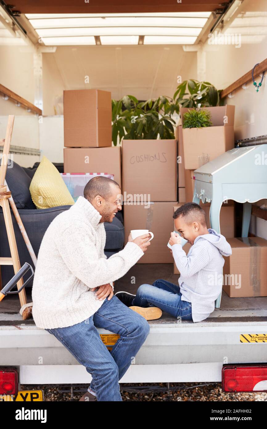 Vater und Sohn sitzen auf Heckklappe Ausbau Lkw mit Drink am Umzugstag Stockfoto