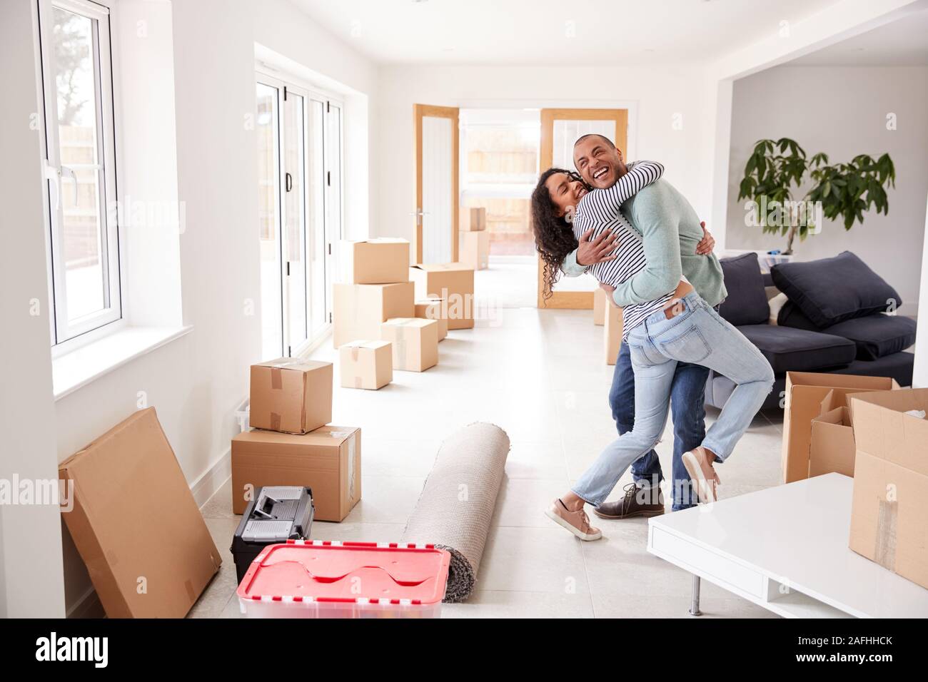 Paar durch Boxen im neuen Haus umgeben umarmen am Umzugstag Stockfoto