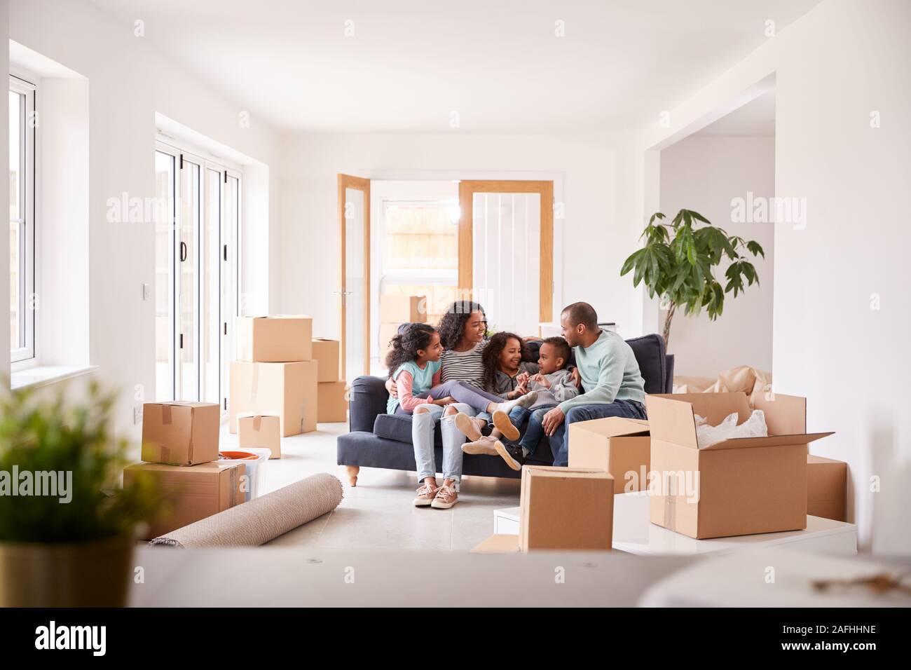 Familie eine Pause und Sitzen auf einem Sofa Feiern in neue Home Gemeinsam Verschieben Stockfoto