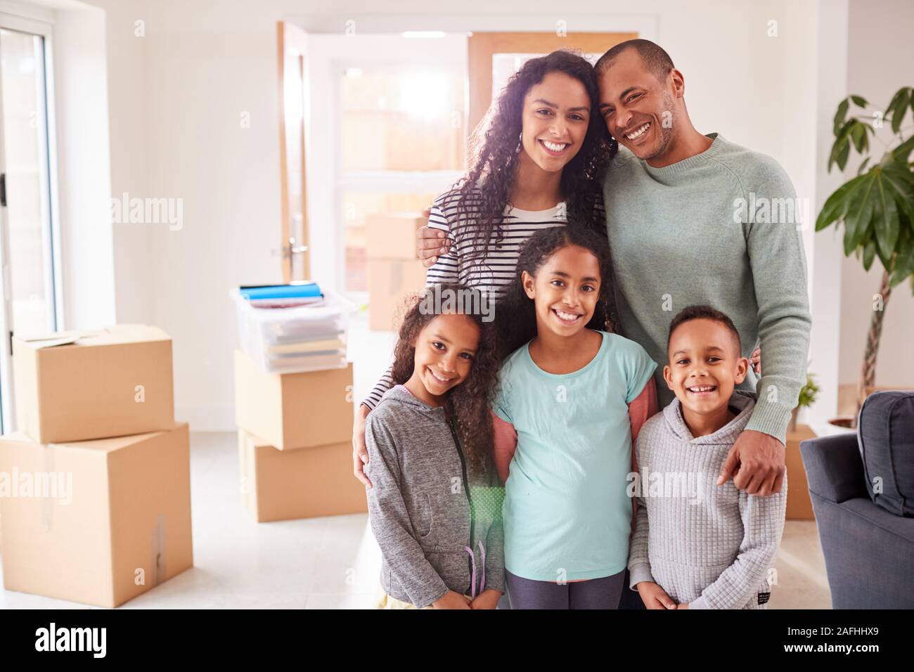 Porträt der Familie umgeben von Boxen im Raum stehen am Umzugstag Stockfoto