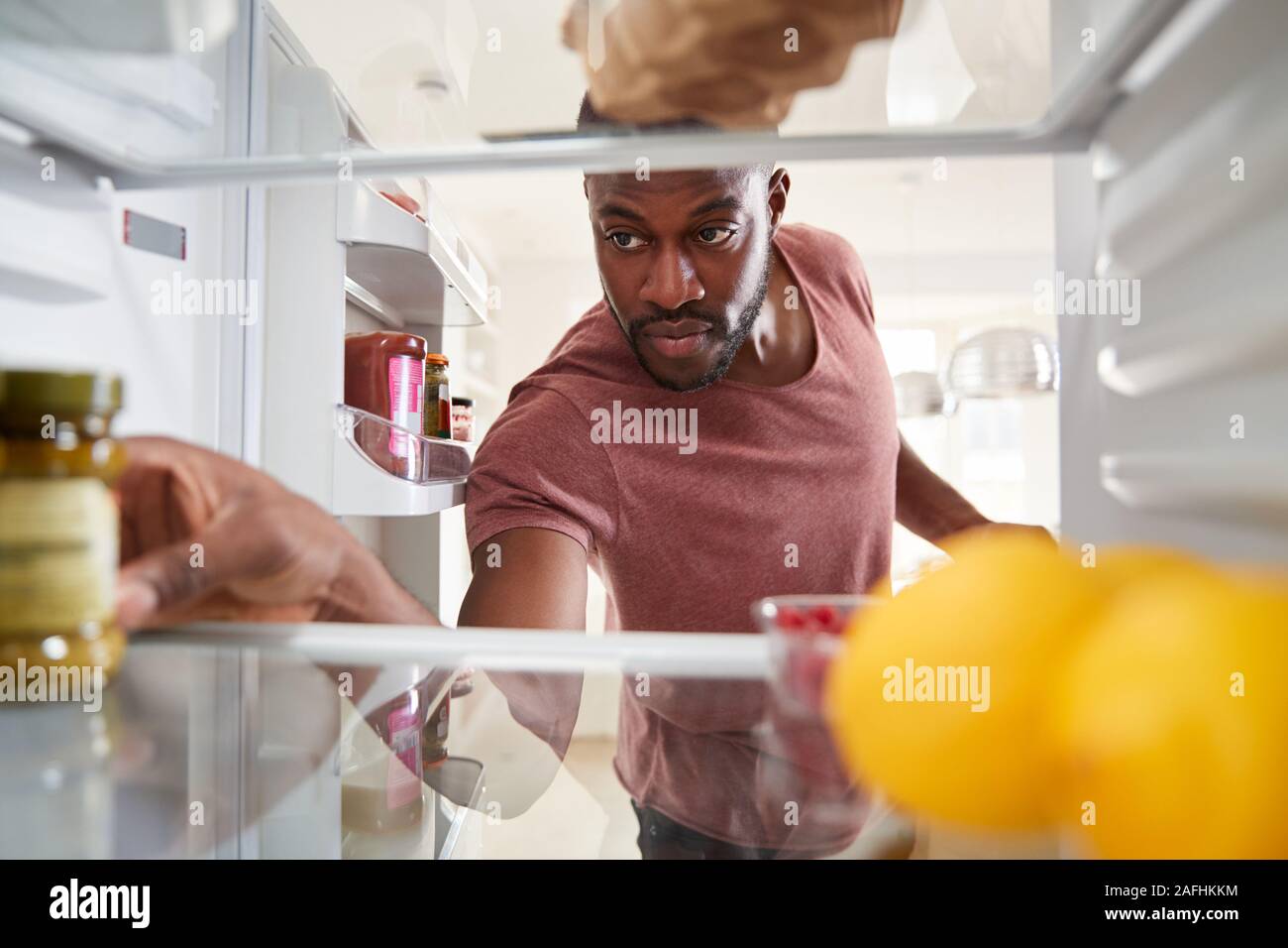 Blick aus dem Inneren des Kühlschranks als Mensch öffnet Tür und Entpackt Shopping Bag von Lebensmitteln suchen Stockfoto