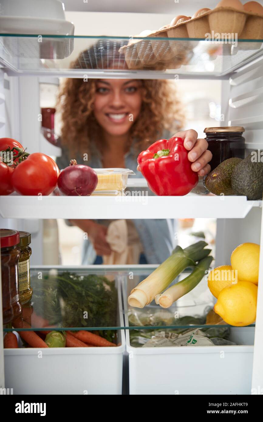 Blick aus dem Inneren der Kühlschrank als Frau öffnet Tür und Entpackt Shopping Bag von Lebensmitteln suchen Stockfoto