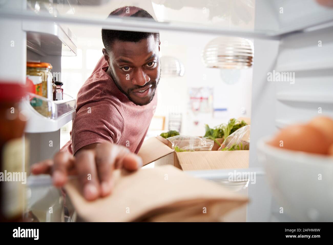 Blick aus dem Inneren der Kühlschrank als Mann packt Online Home Food Delivery Suchen Stockfoto