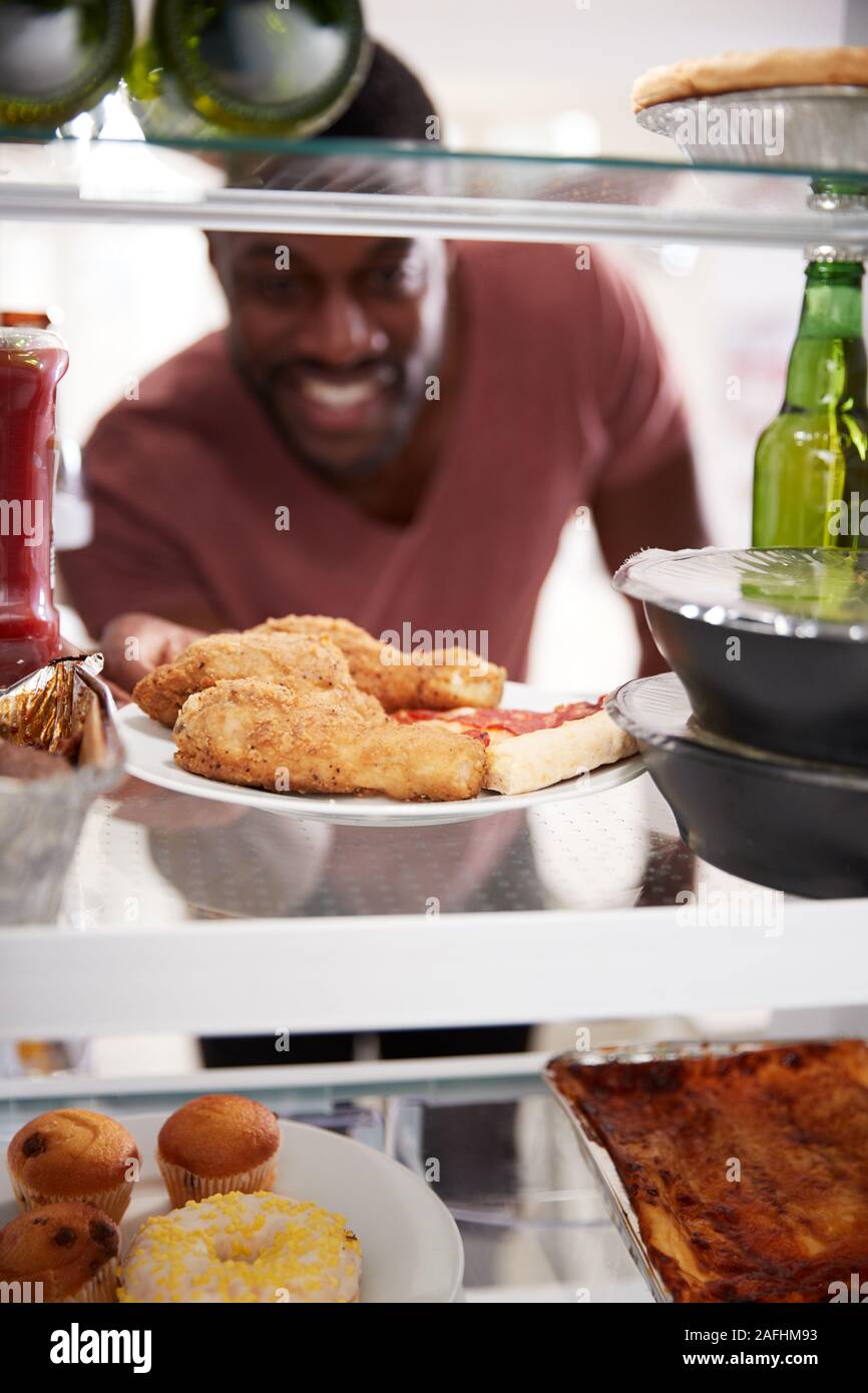 Anzeigen, die von der Innenseite der Kühlschrank gefüllt mit Essen zum Mitnehmen als Mensch öffnet Tür Stockfoto