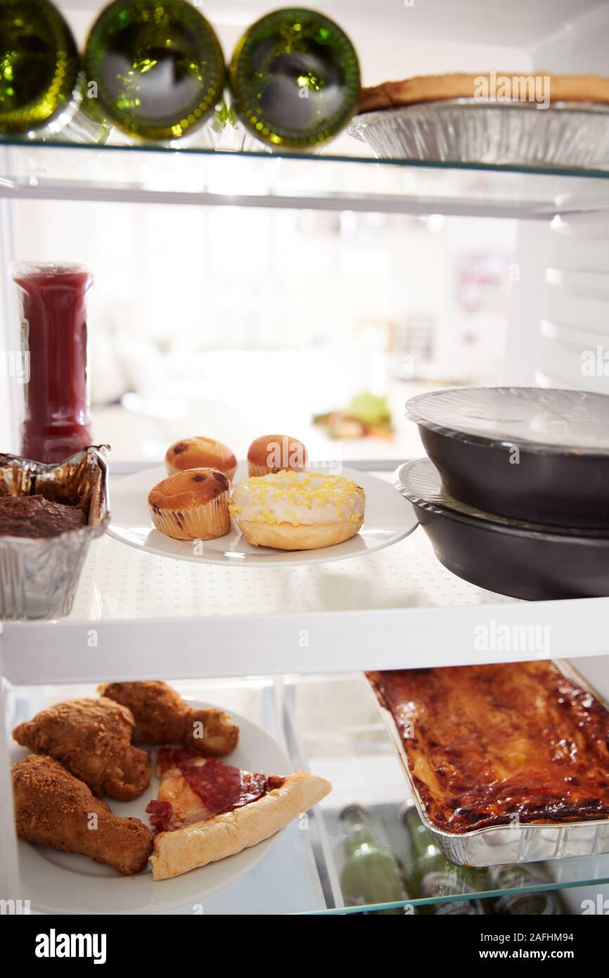 Blick in Kühlschrank von ungesunden Essen zum Mitnehmen und Bier in den Regalen Stockfoto