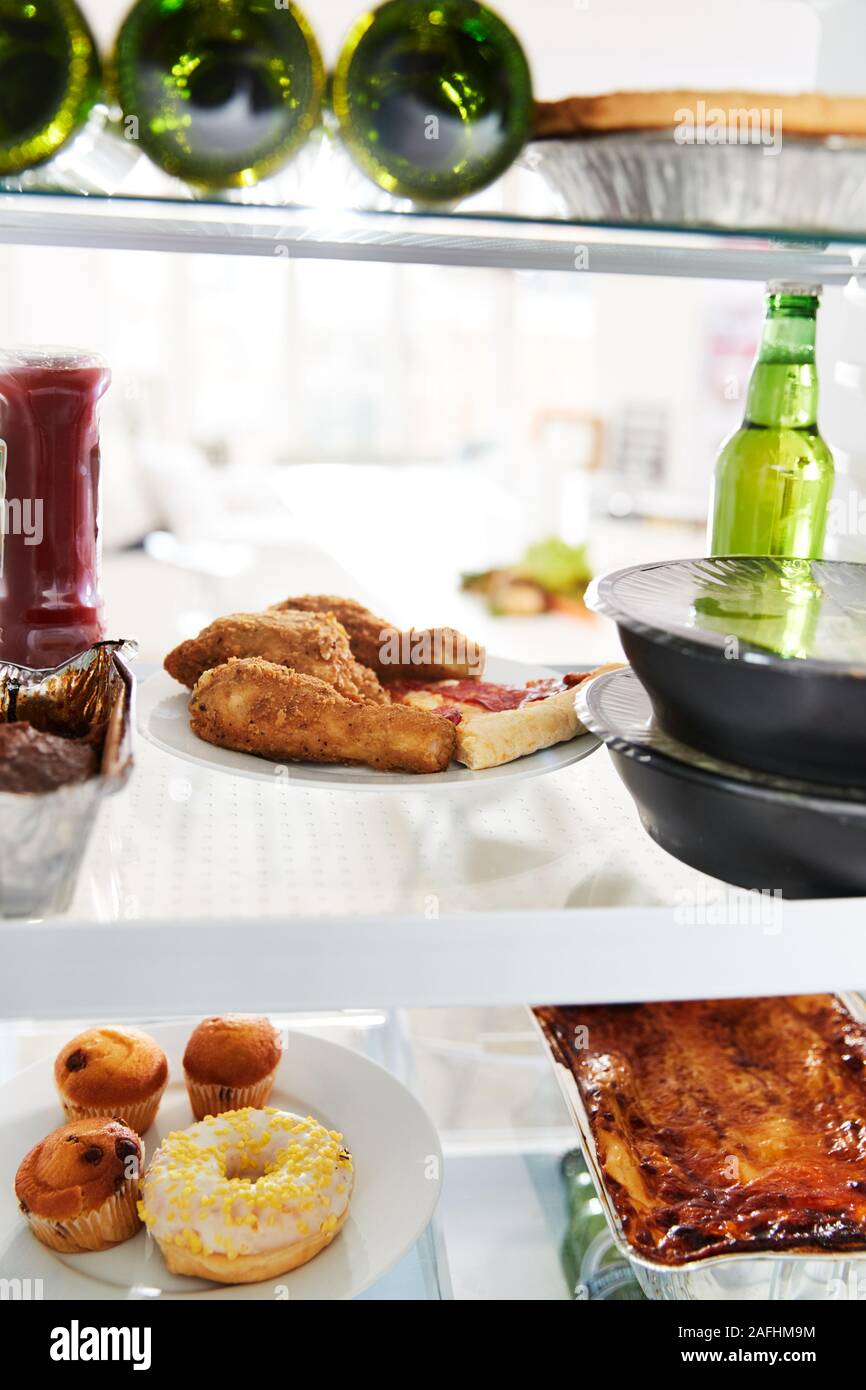 Blick in Kühlschrank von ungesunden Essen zum Mitnehmen und Bier in den Regalen Stockfoto