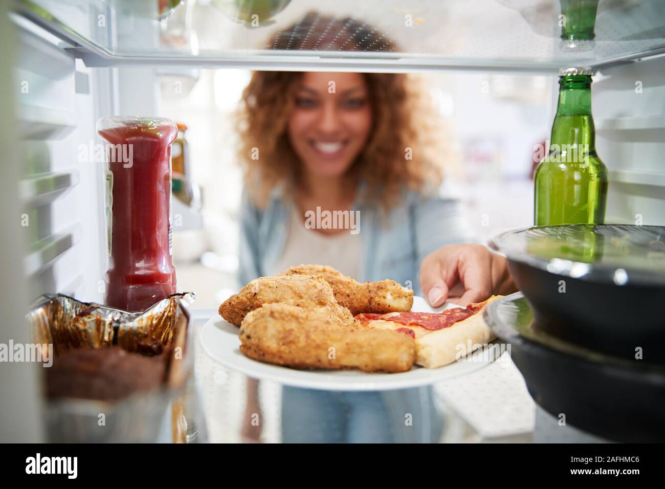Anzeigen, die von der Innenseite der Kühlschrank gefüllt mit Essen zum Mitnehmen als Frau öffnet Tür Stockfoto