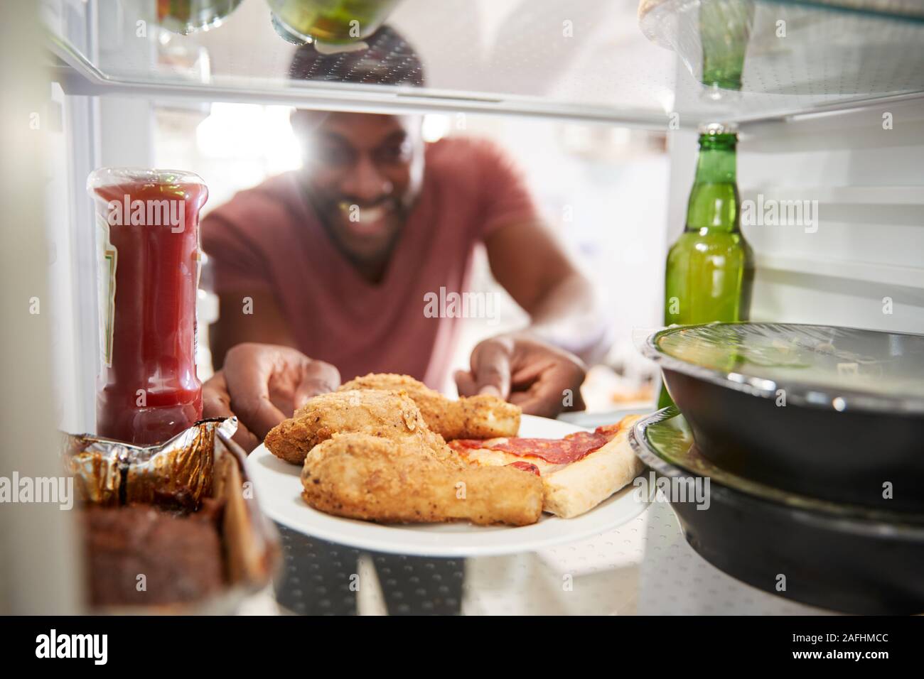 Anzeigen, die von der Innenseite der Kühlschrank gefüllt mit ungesunden Essen zum Mitnehmen als Mensch öffnet Tür Stockfoto