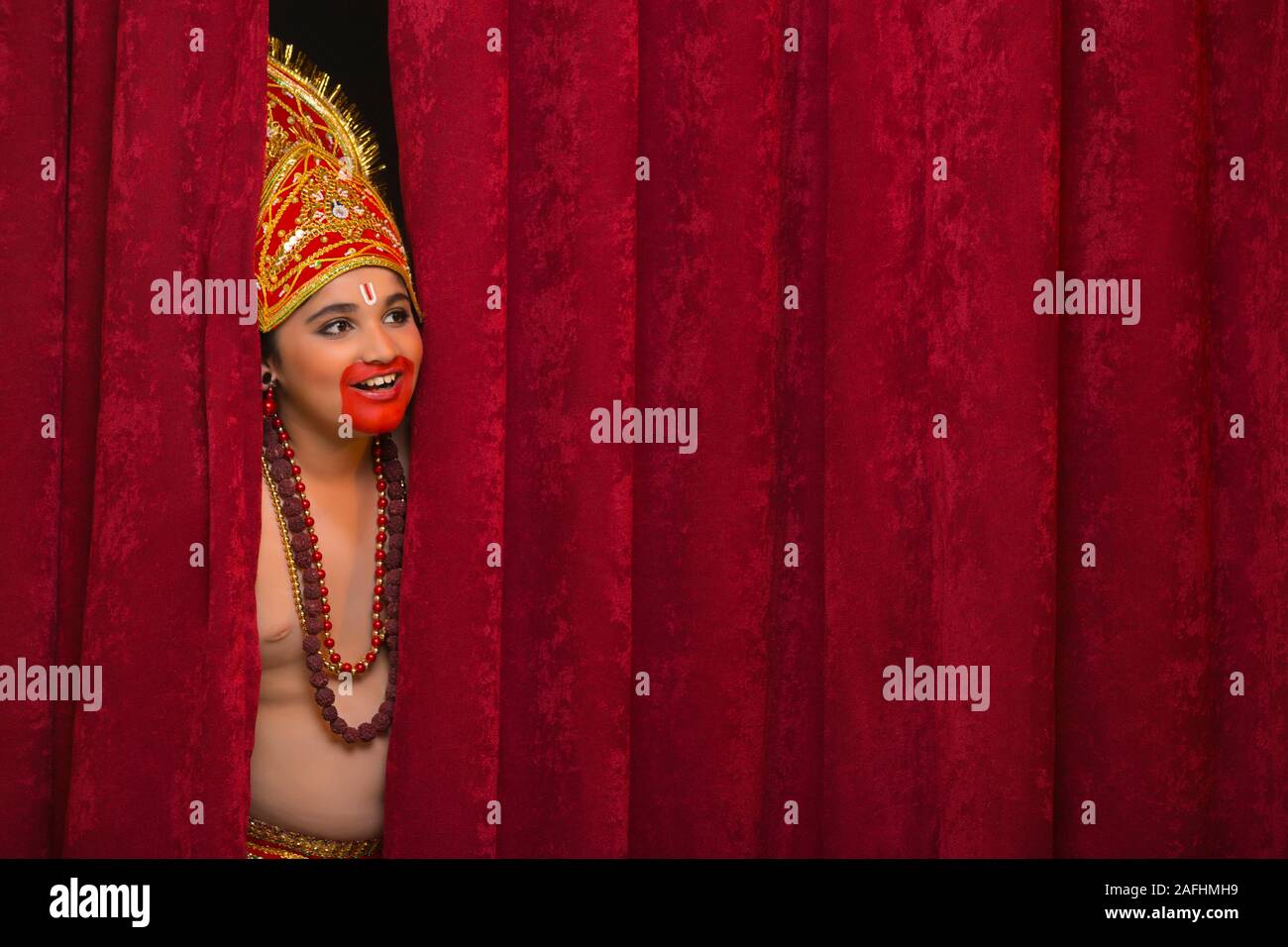 Kind verkleidet als hanuman peeking out von Gardinen Stockfoto