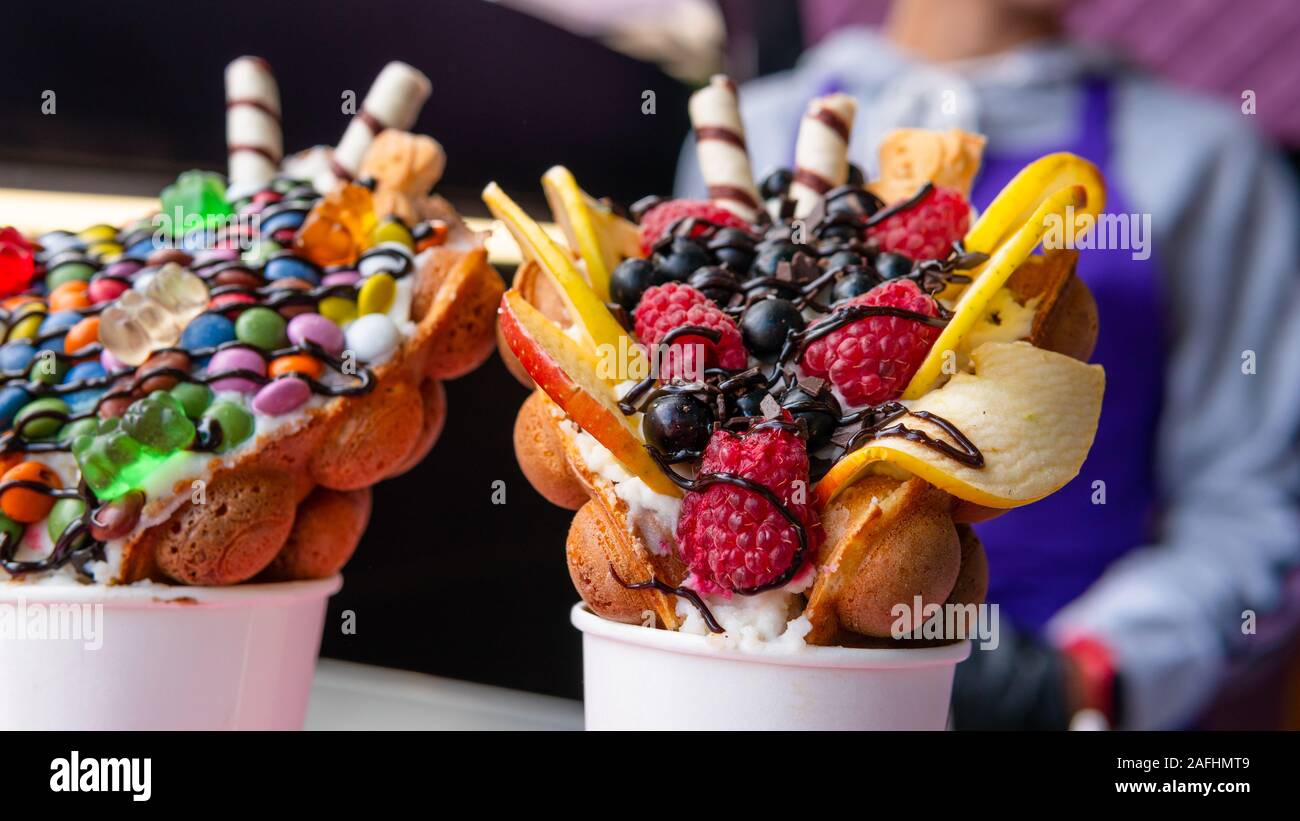 Bubble Waffeln mit Himbeeren, Schokolade und Marshmallows in white paper Cups sind auf offene Küche Food Festival verkauft. Hong Kong Waffeln. Anhand von quantitativen Simulatio Stockfoto