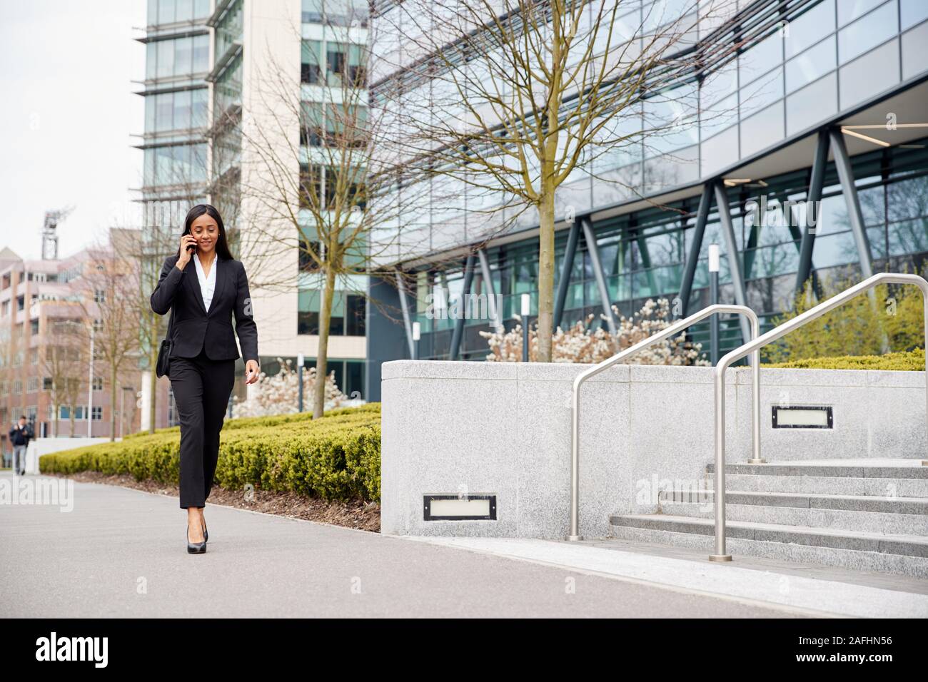 Geschäftsfrau Pendeln zur Arbeit Gespräch am Handy außerhalb Modernes Bürogebäude Stockfoto