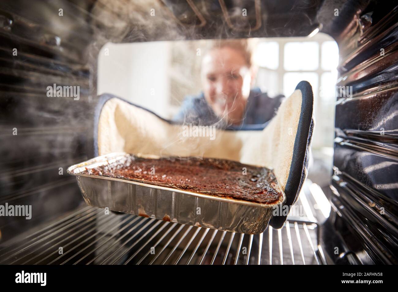 Betrachten aus dem Inneren Ofen als Frau brennt Abendessen Stockfoto