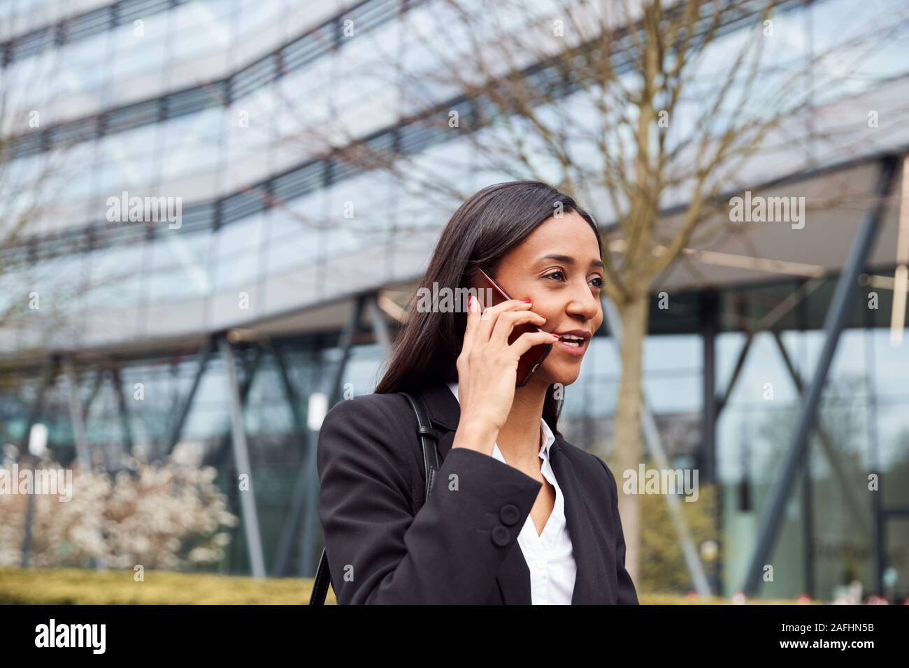 Geschäftsfrau Pendeln zur Arbeit Gespräch am Handy außerhalb Modernes Bürogebäude Stockfoto