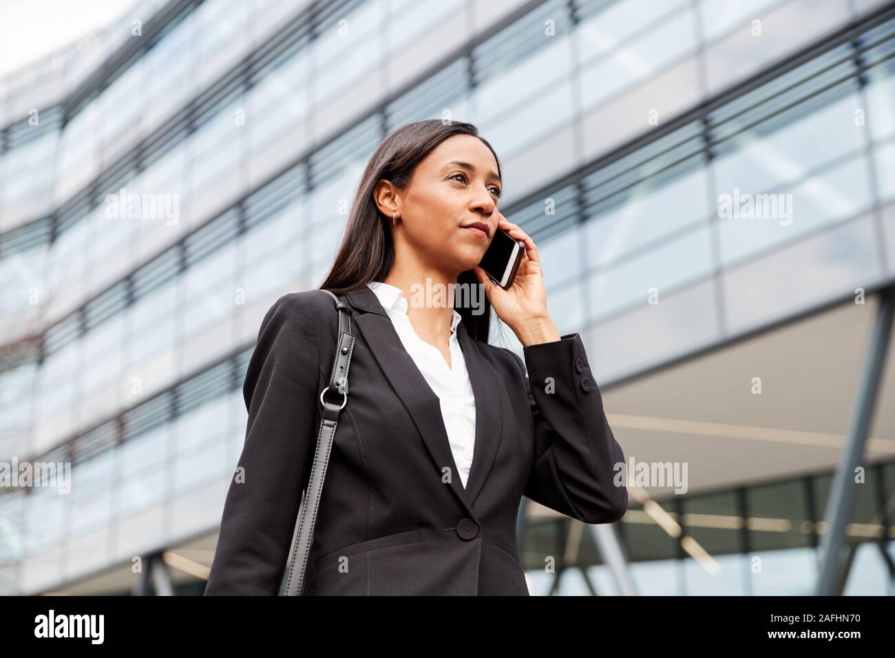 Geschäftsfrau Pendeln zur Arbeit Gespräch am Handy außerhalb Modernes Bürogebäude Stockfoto
