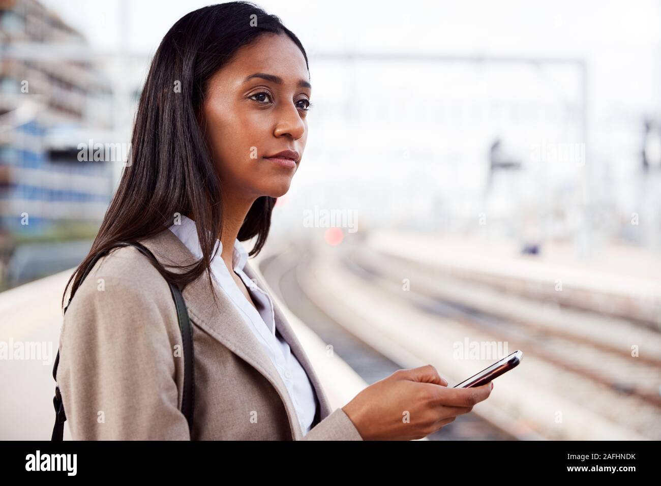 Geschäftsfrau auf Bahnsteig Pendeln zur Arbeit Buchung Ticket auf dem Mobiltelefon Stockfoto