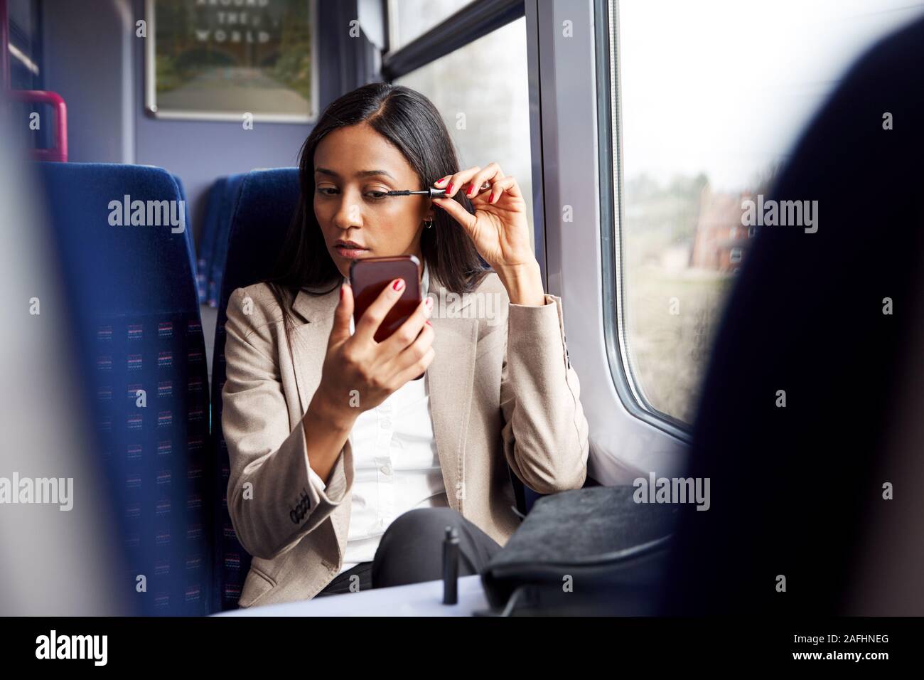 Geschäftsfrau sitzt in dem Zug pendeln zur Arbeit setzen auf Make-up Stockfoto