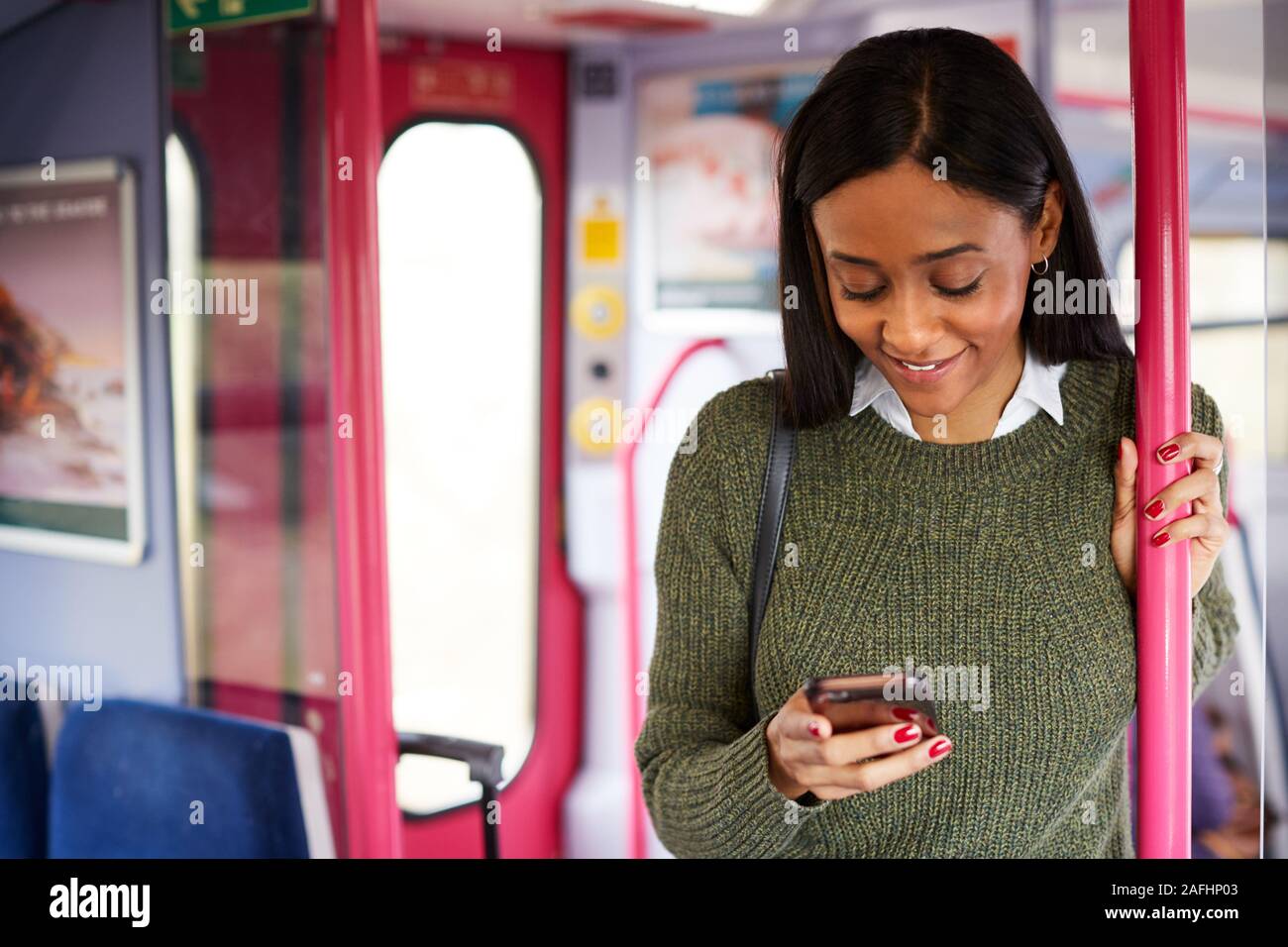 Weibliche Passagier durch Türen in Zug am Handy suchen Stehend Stockfoto