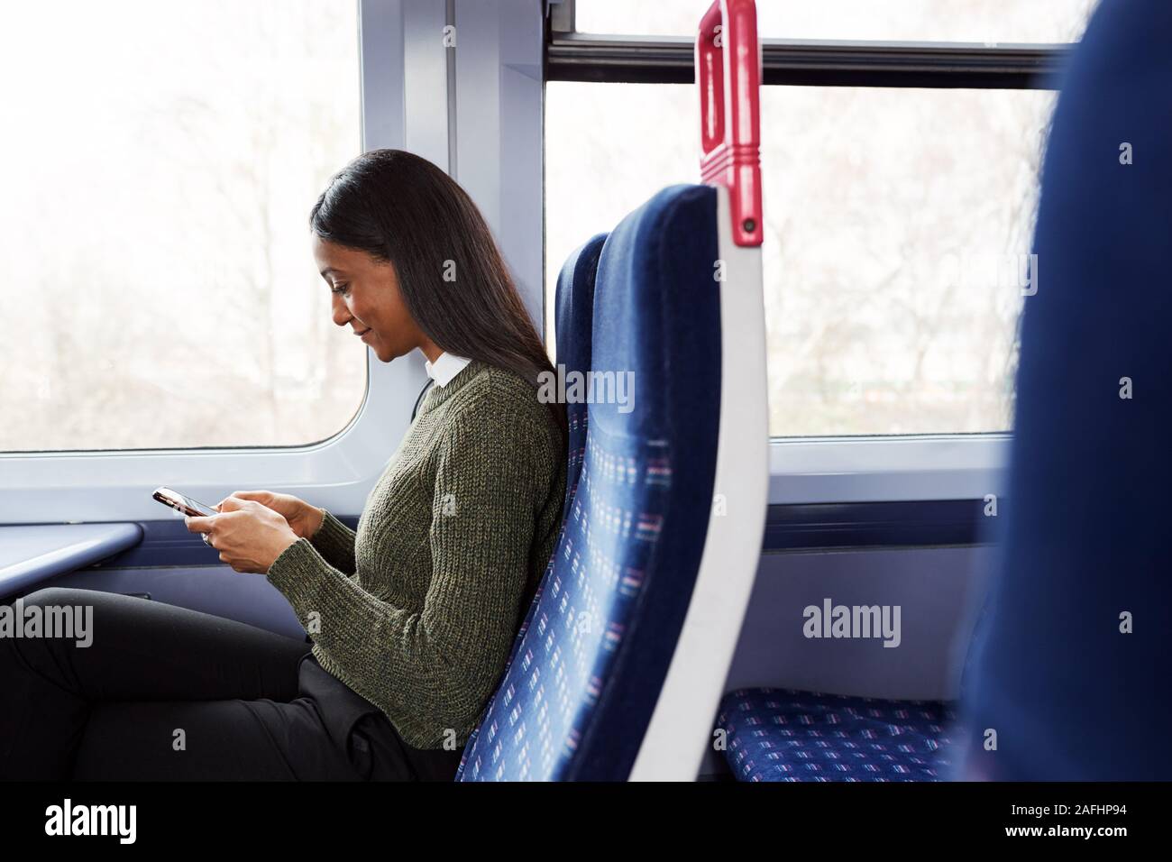 Weibliche Passagier sitzt im Zug am Handy suchen Stockfoto