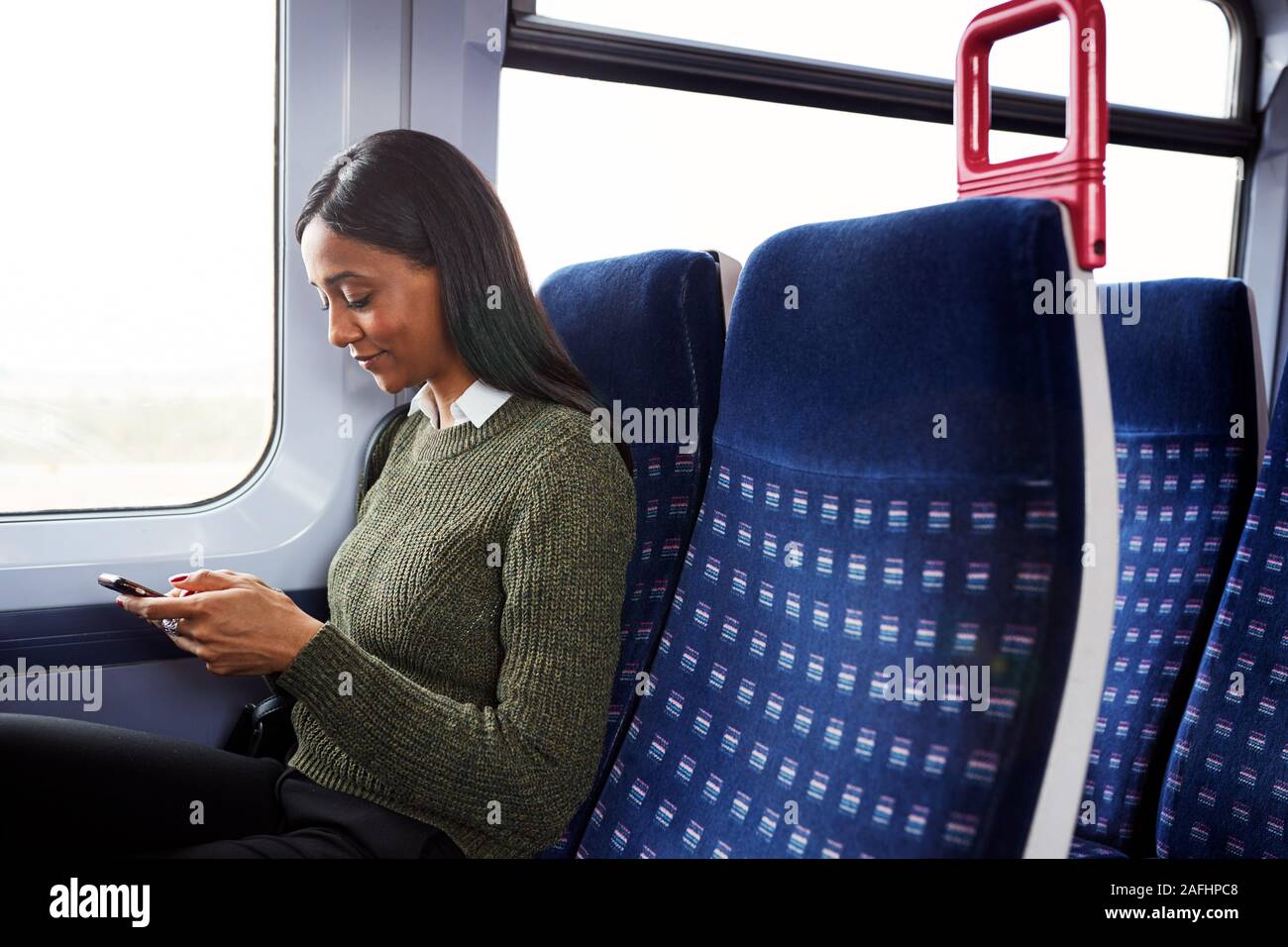 Weibliche Passagier sitzt im Zug am Handy suchen Stockfoto