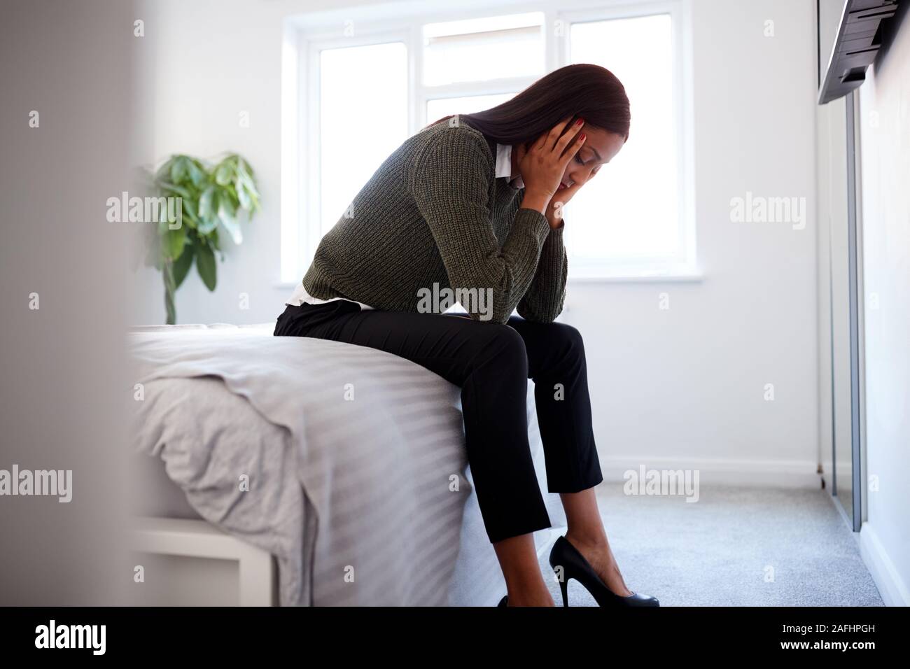 Betonte Geschäftsfrau mit Kopf in den Händen sitzen am Rande von Bett zu Hause Stockfoto