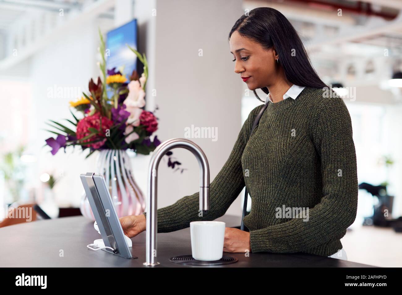 Geschäftsfrau Heiß Trinken von automatisierten Dispenser im Büro Stockfoto