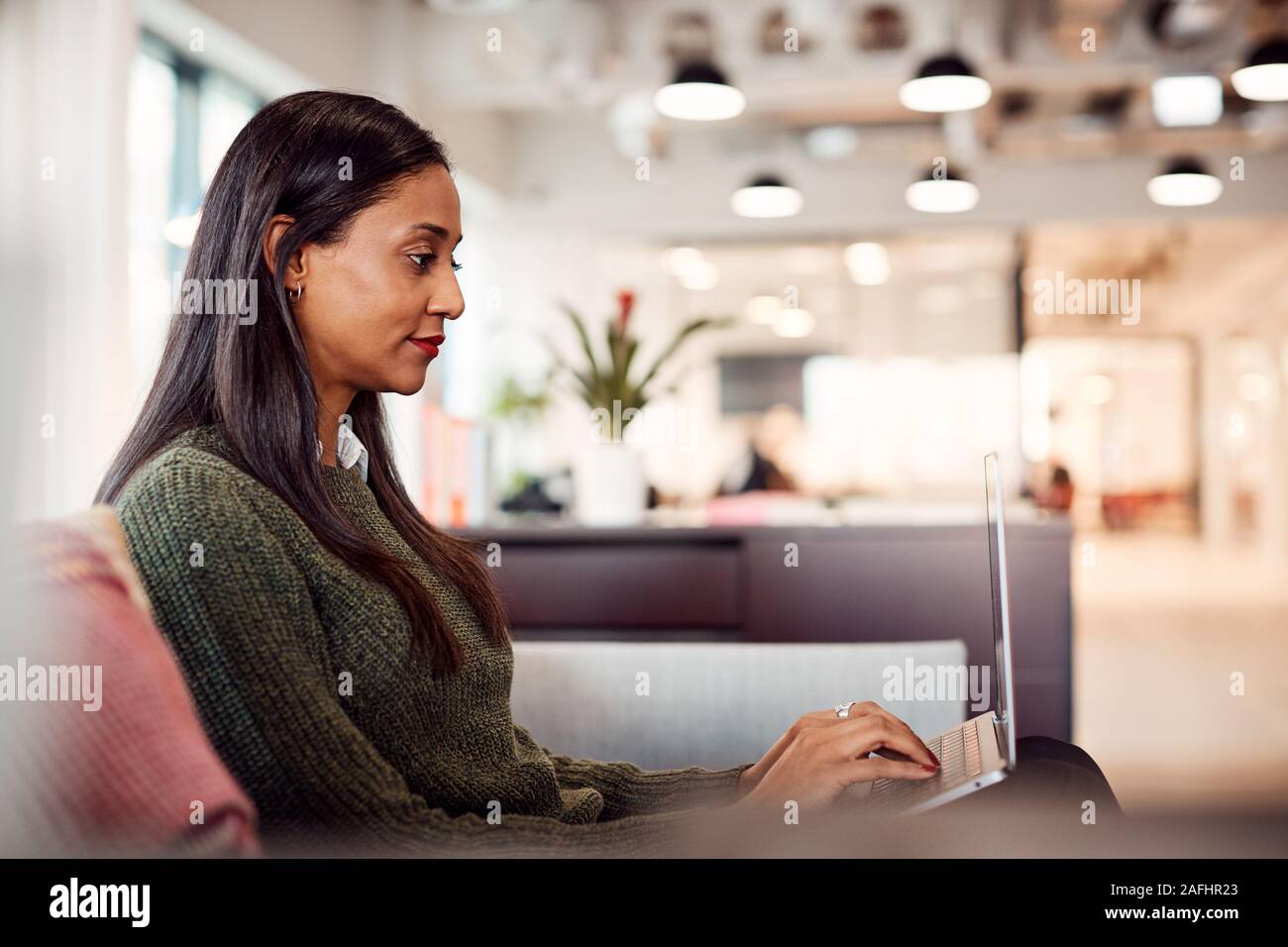 Geschäftsfrau, Sitzen auf einem Sofa Arbeiten am Notebook am Schreibtisch In gemeinsamen Arbeitsbereich Büro Stockfoto