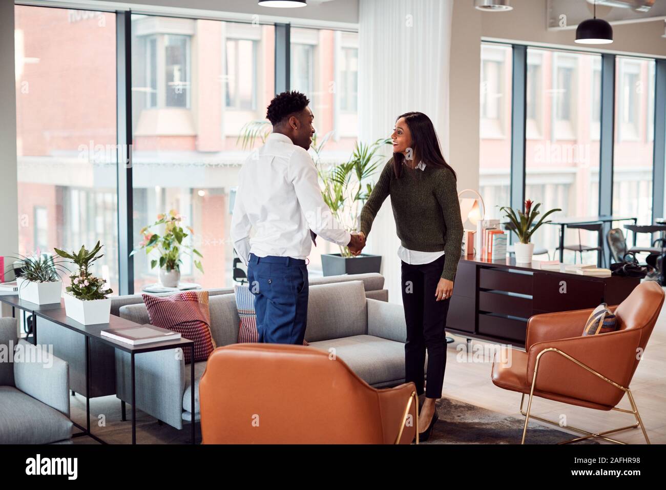 Geschäftsfrau Händeschütteln mit männlichen Interview Kandidat in der Sitzecke moderne Büro Stockfoto