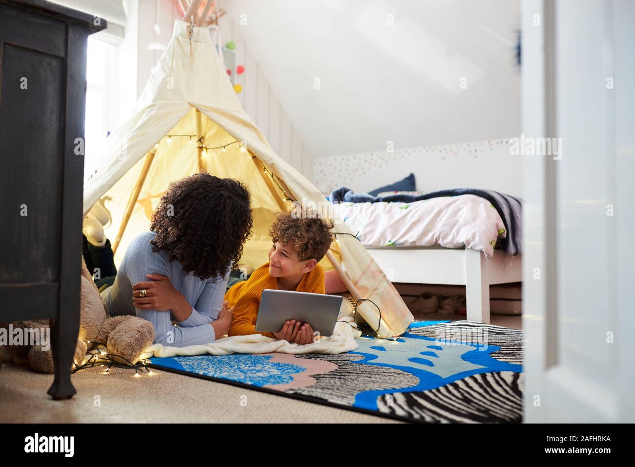 Single Mutter spielt mit Sohn auf Digital Tablet in der Höhle im Schlafzimmer zu Hause Stockfoto