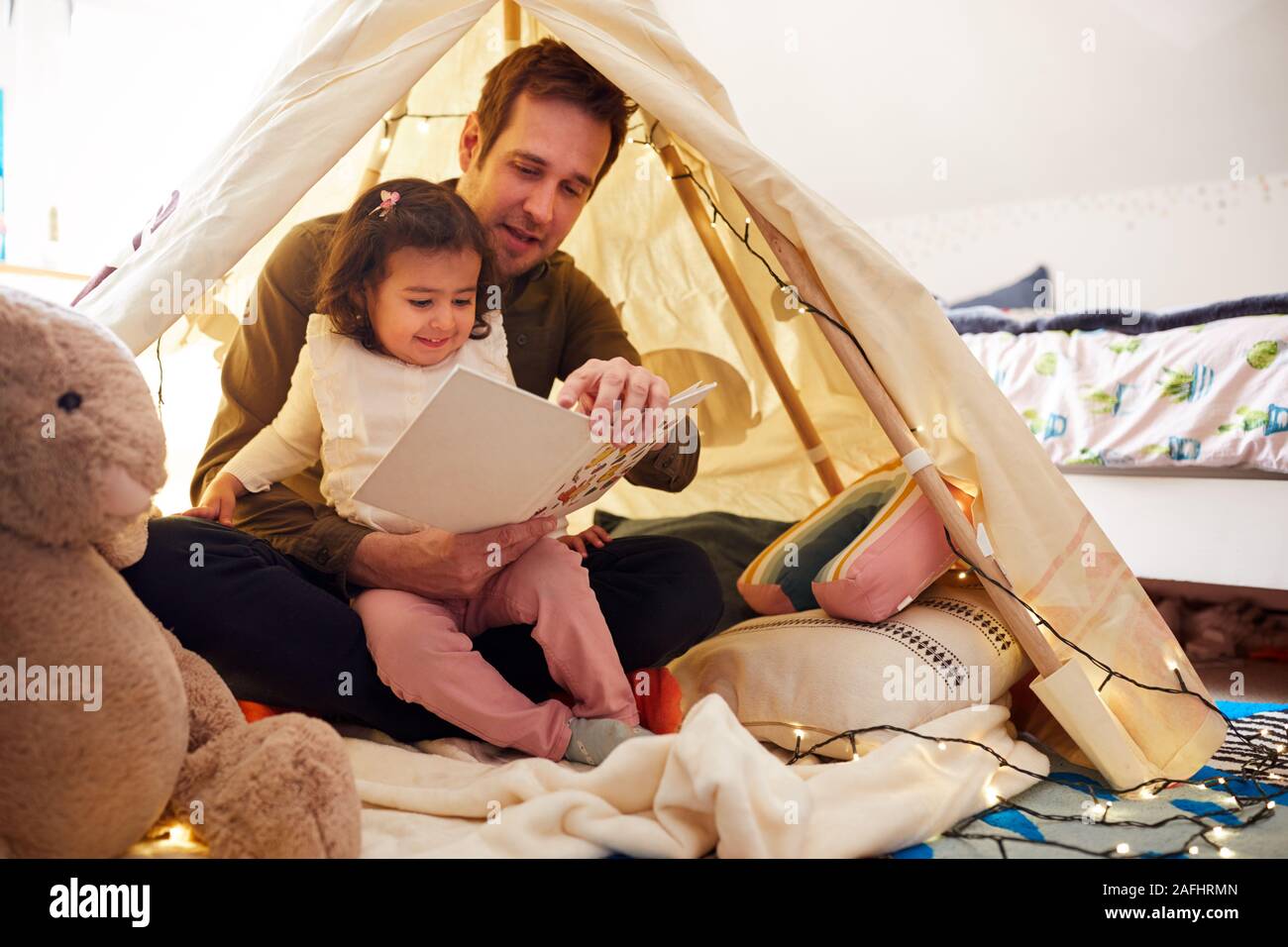 Einzelnen Vater Lesung mit Tochter in der Höhle im Schlafzimmer zu Hause Stockfoto