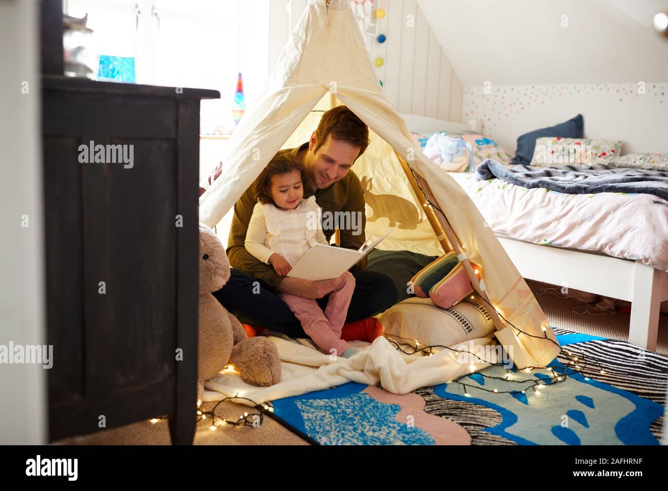 Einzelnen Vater Lesung mit Tochter in der Höhle im Schlafzimmer zu Hause Stockfoto
