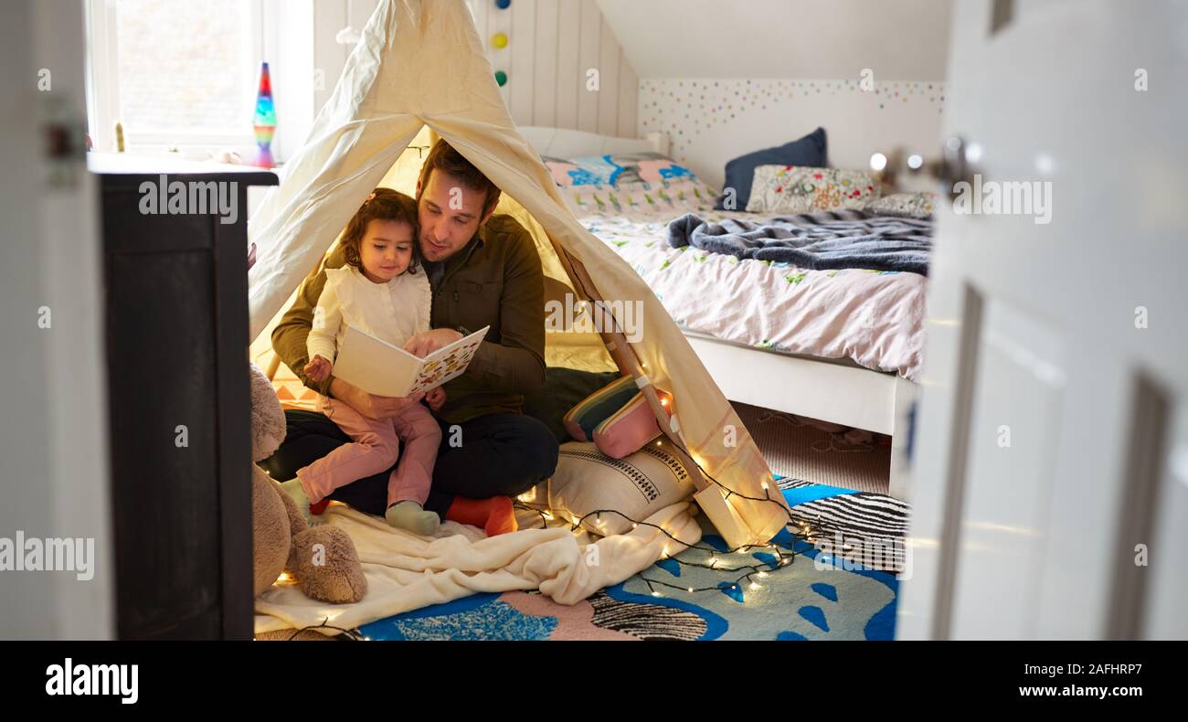 Einzelnen Vater Lesung mit Tochter in der Höhle im Schlafzimmer zu Hause Stockfoto