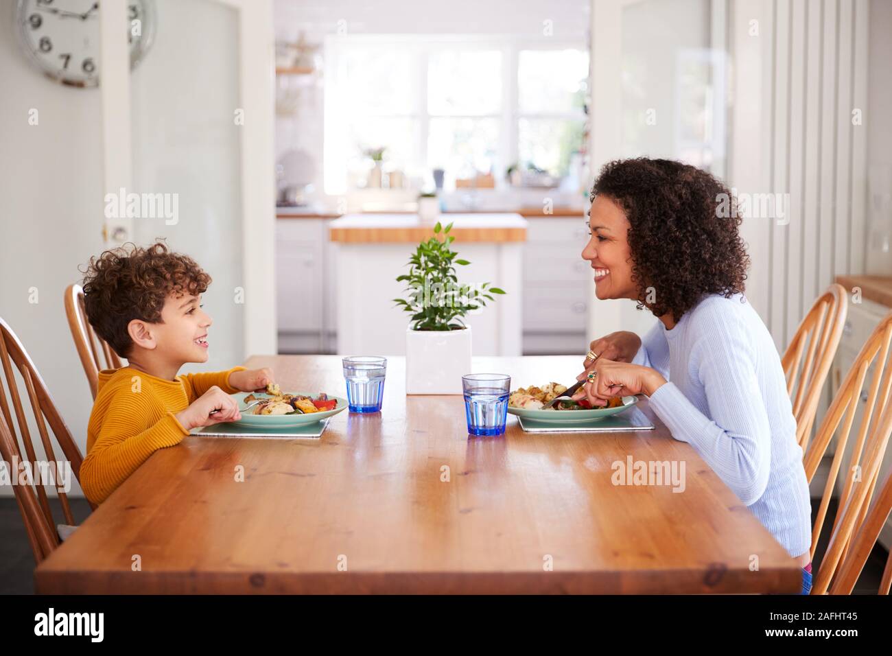 Einzelne Mutter Sitzen am Tisch essen Mahlzeit mit Sohn in der Küche zu Hause. Stockfoto