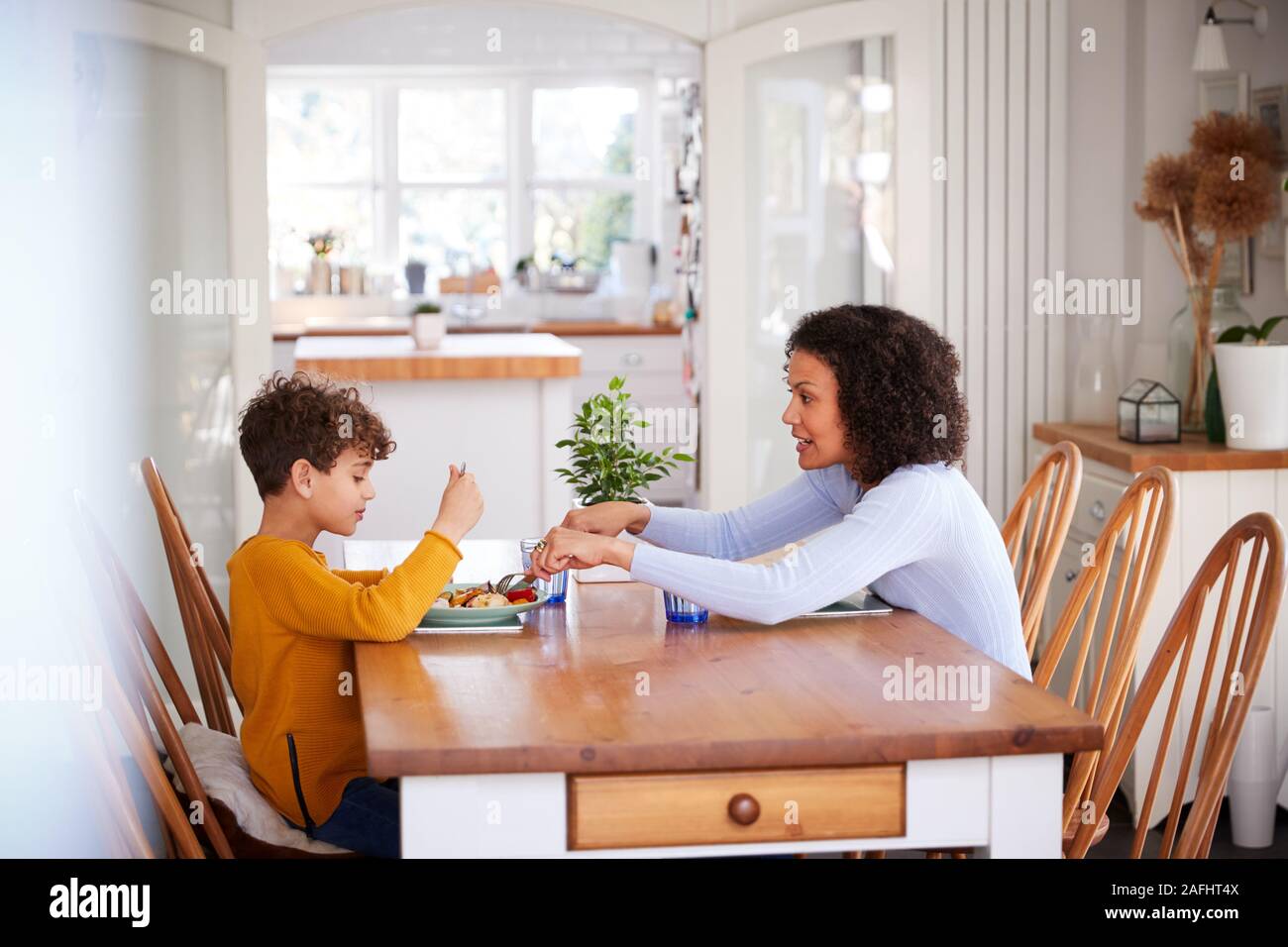 Einzelne Mutter Sitzen am Tisch essen Mahlzeit mit Sohn in der Küche zu Hause. Stockfoto