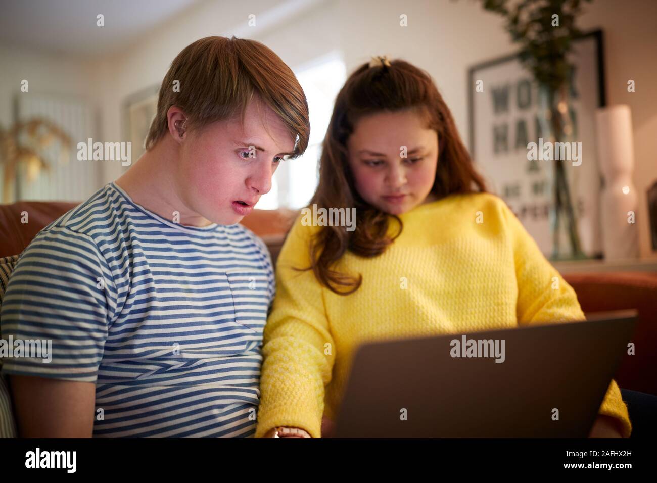 Junge Abstiegsyndrom Paar sitzt auf einem Sofa mit Laptop zu Hause Stockfoto