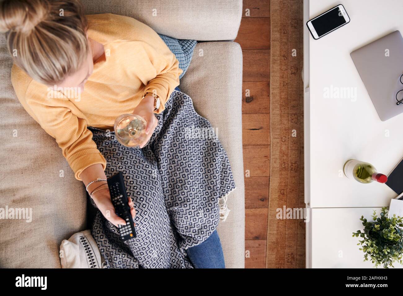 Overhead Shot Suchen auf Frau zu Hause auf dem Sofa liegend vor dem Fernseher sitzen und Wein trinken Stockfoto