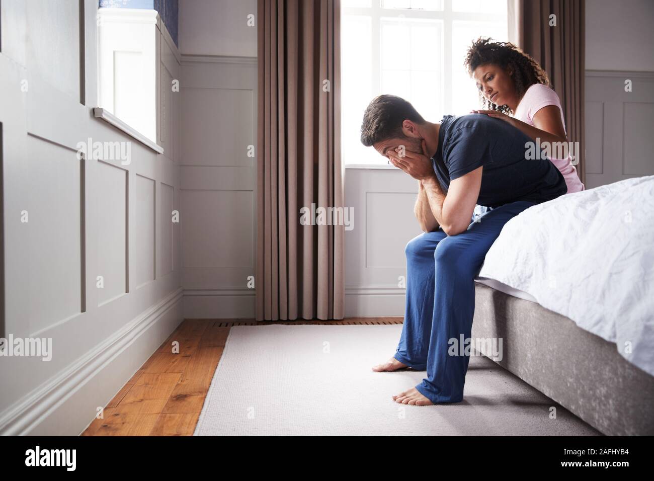 Frau tröstend Mann mit Schlafanzug mit Depression sitzen auf dem Bett zu Hause Leiden Stockfoto