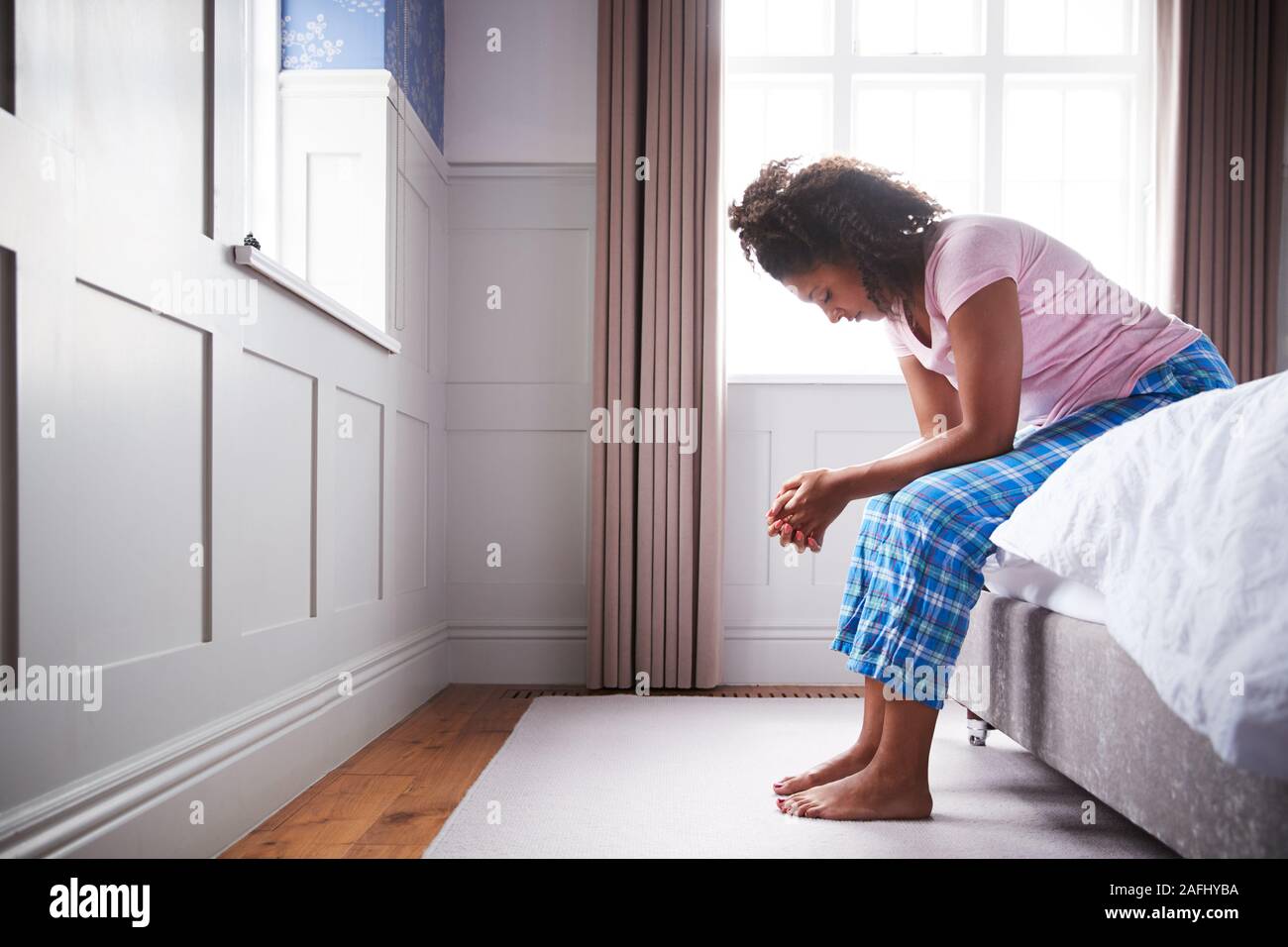 Frau mit Schlafanzug mit Depression sitzen auf dem Bett zu Hause Leiden Stockfoto