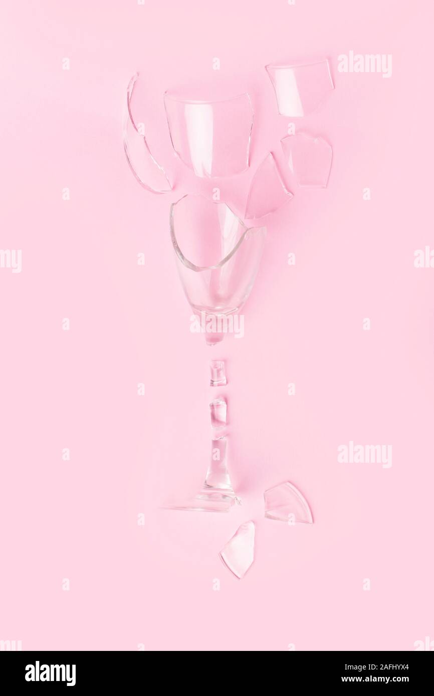 Ein Glas Champagner in Stücke auf eine trendige Pastell rosa Hintergrund gebrochen. Flach Stil Stockfoto