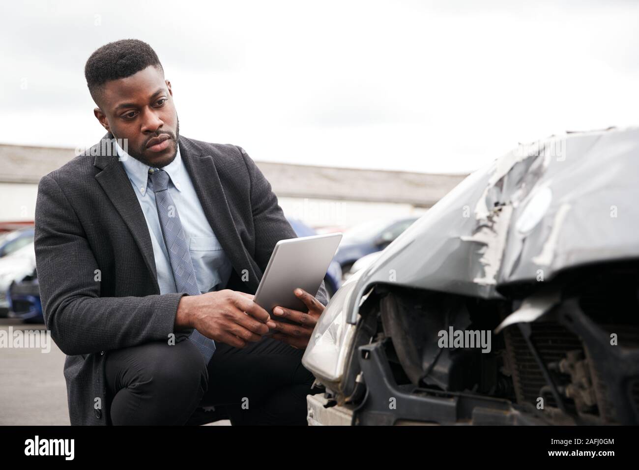 Männliche Insurance Loss Adjuster mit digitalen Tablet Inspektion Schaden an dem Auto von Motor Unfall Stockfoto